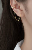 Gold hoop earring worn by a person with dark hair against a neutral background