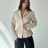 Woman wearing a beige blazer against a white background
