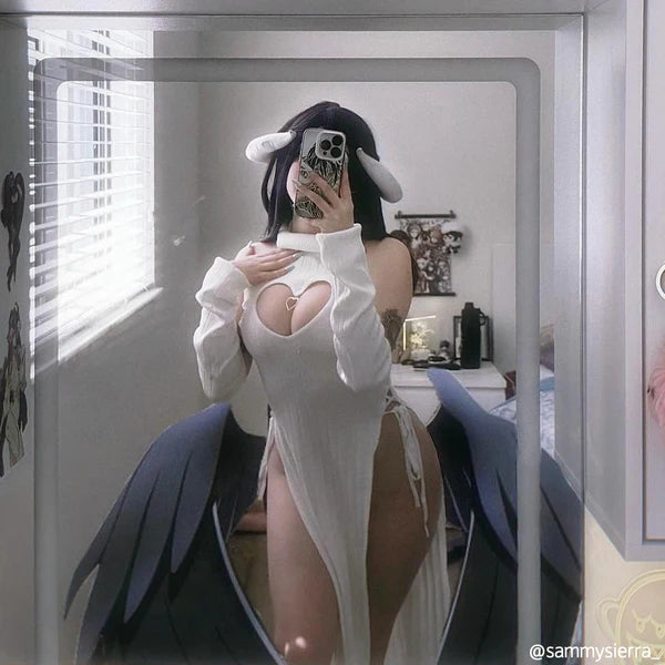 Person in a white outfit with cut-out design taking a mirror selfie.