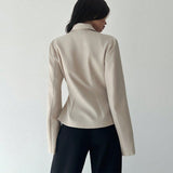 Person wearing a beige blazer and black pants on a plain background