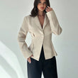 Woman wearing a beige blazer over a black top on a white background