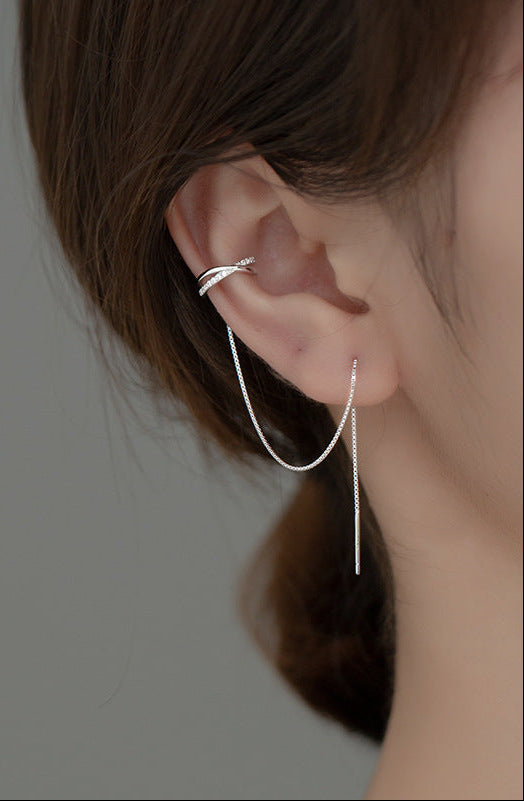 Close-up of an ear wearing a silver earring with a blurred background